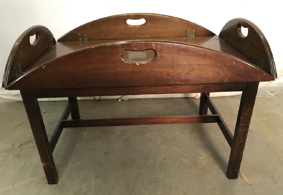 Vintage Butler Style Coffee Table: Table top folds up & has handles to function as tray. Piece is vintage. Contains evident scratches and surface chips. Table top has oval shape when fully open. Measures approx 40 inches long 30 inches