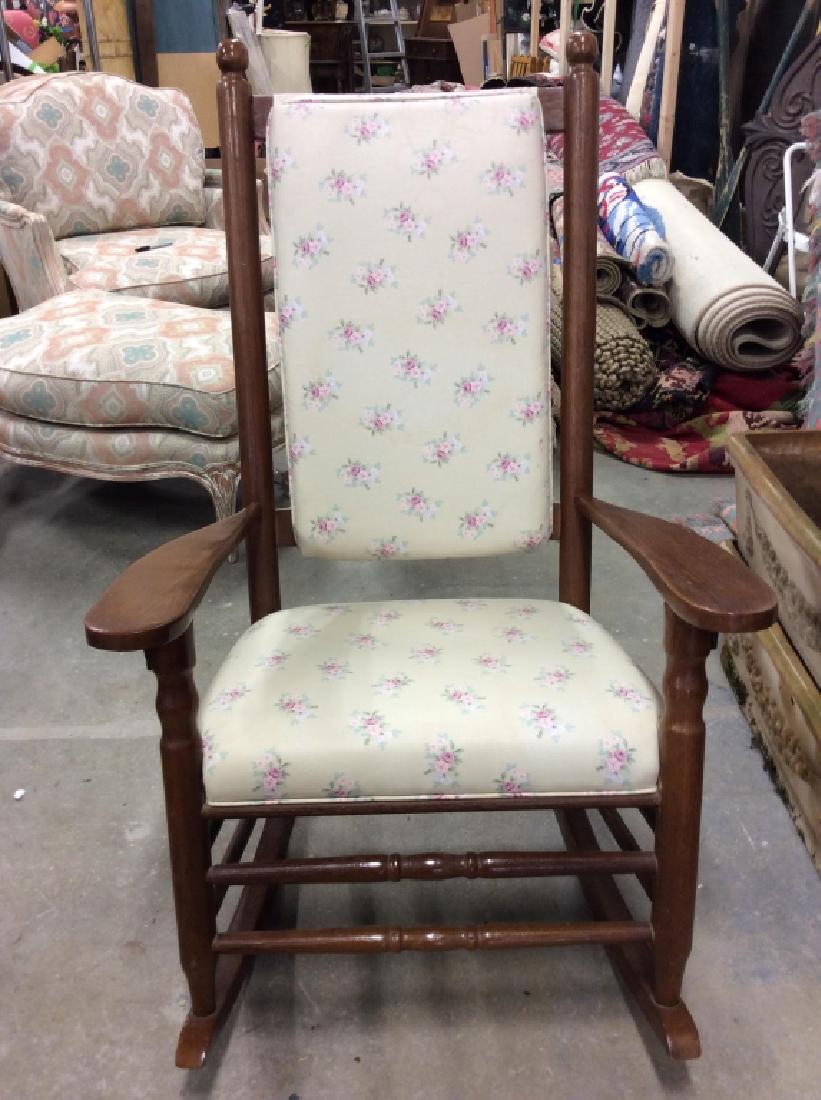 Vintage Floral Detailed Rocking Chair: Chair has wooden frame. Has banana cream toned upholstery with floral detail. Cushions are loose. Has some stains. Measures approx 44 inches tall 28 inches wide 33 inches deep. Contains some scratches