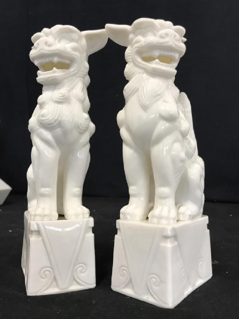 Pair of White Ceramic Foo Dogs: Pair of white ceramic Foo Dogs, seated on block pedestals, revealing teeth and flattened ears, each measures 3 1/2 in x 9 3/4 in, x 2 1/2 in, undersides each marked with 757W, good condition, Asian Ce