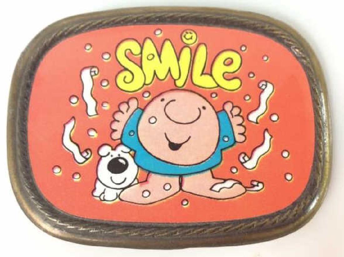 Belt Buckle, ‘Smile’ Cartoon Illustration: Belt Buckle, ‘Smile’ Cartoon Illustration. Dark bronze toned metal buckle with bright print of illustration featuring orange background, a cartoon of a boy and his dog, reads ‘Smile’ over thei