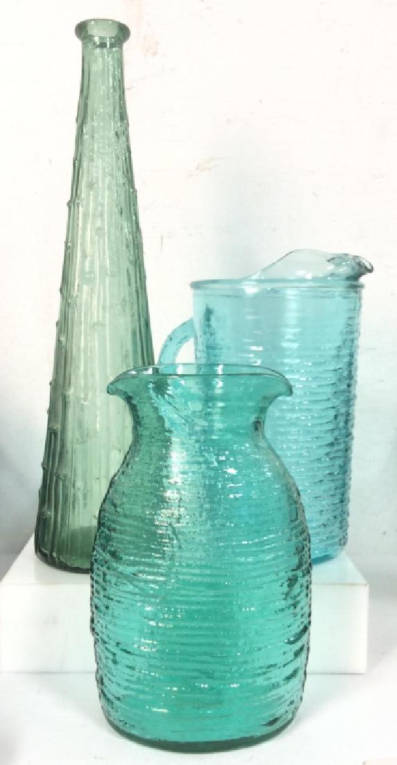 Lot 3 Blue Toned Art Glass Accessories: Lot 3 Blue Toned Art Glass Accessories. Blue and green art glass, one piece handcrafted, two pressed glass, one glass water/drinks pitcher, two vases, with ridged texture. Kitchen accessories, decorat