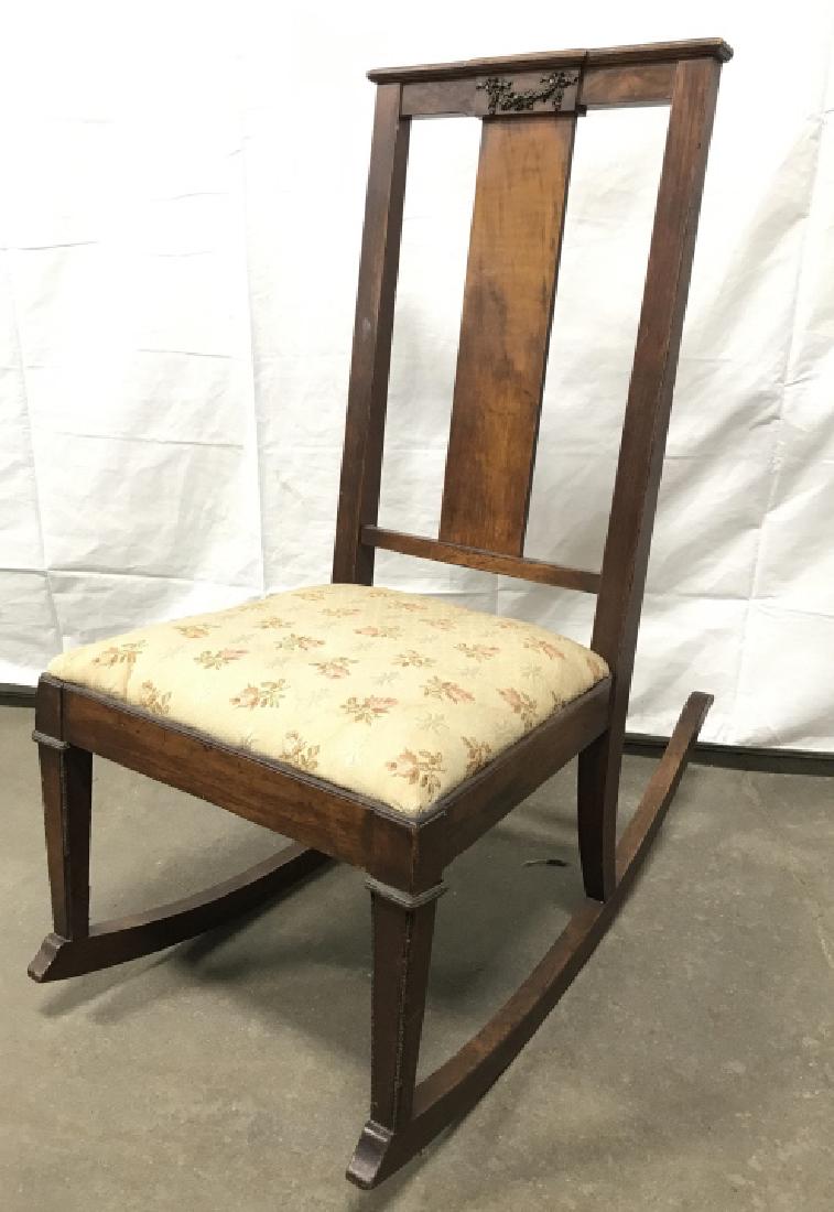 Antique Wooden Rocker With Upholstered Seat: Antique Wooden Rocker in dark toned wood, Carved detail at top , and Upholstered Seat. Stains to seat material, some minor wear and nicks to wood due to age. Measures approx 37.5 inches tall x 18 inch