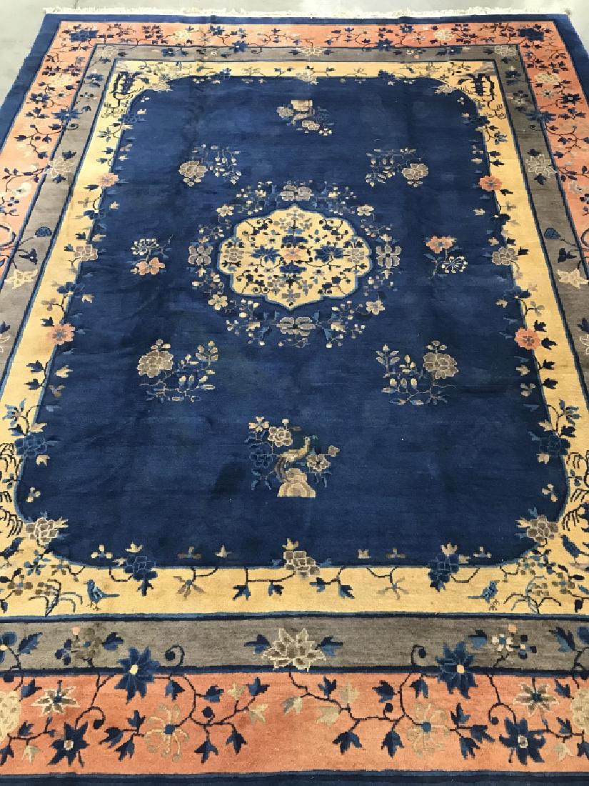 Antique Wool Chinese Art Deco Peking Carpet: Antique Wool Chinese Art Deco Peking Carpet with fringe, featuring navy blue base with salmon, tan and golden toned borders with intricate floral, Bird, and pagoda motif. Center medallion depicts an i