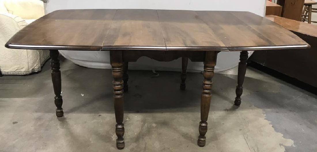 Extendable Drop Leaf Wooden Dining Table: Drop leaf wooden rectangular dining table with two removable boards for adjustable extension. Dark wood with carved details in the legs. Some scuffs and scratches on the tabletop and table feet consis