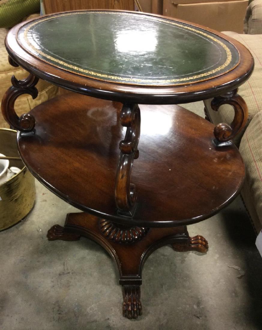 Carved Wooden Two Tier Leather Top Side Table: Side table has green toned top, possibly leather, with gold toned accent. Contains carved S curve detail. Also has claw style feet. Piece is oval shaped. Possibly vintage. Measures approx 28 inches lo