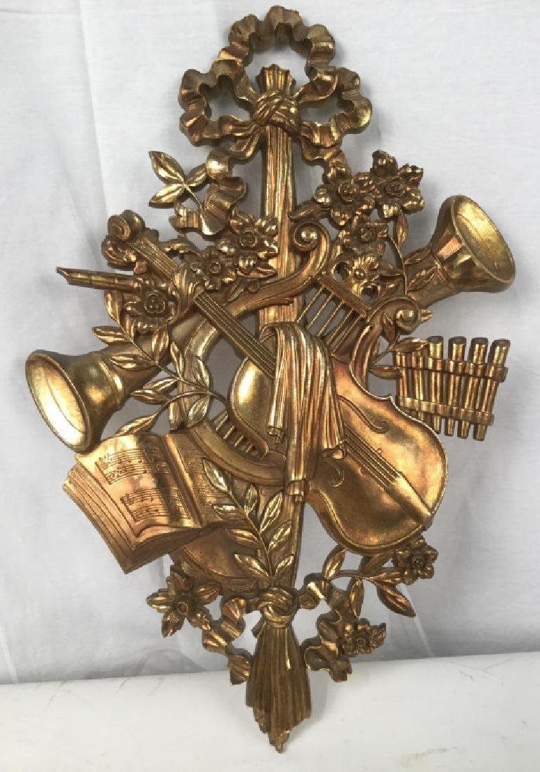 SYROCO WOOD Wall Hanging Of Instruments: SYROCO WOOD Wooden Wall Hanging Of musical instruments amidst flower and ribbon details. Wall hanging is bronze gold in tone. Reverse side has Syroco Wood Label. Wall hanging approx 26.5 inches in hei
