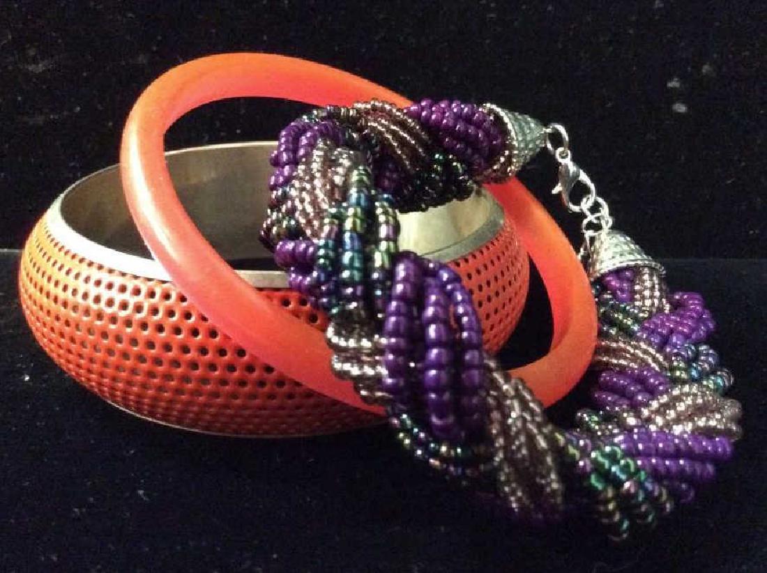Lot 3 Women’s Vintage Costume Jewelry Bracelets: Lot 3 Women’s Vintage Costume Jewelry Bracelets. One beaded bracelet with multiple stands of purples and iridescent black toned beads braided together, with silver toned metal clasp. One red/orange 