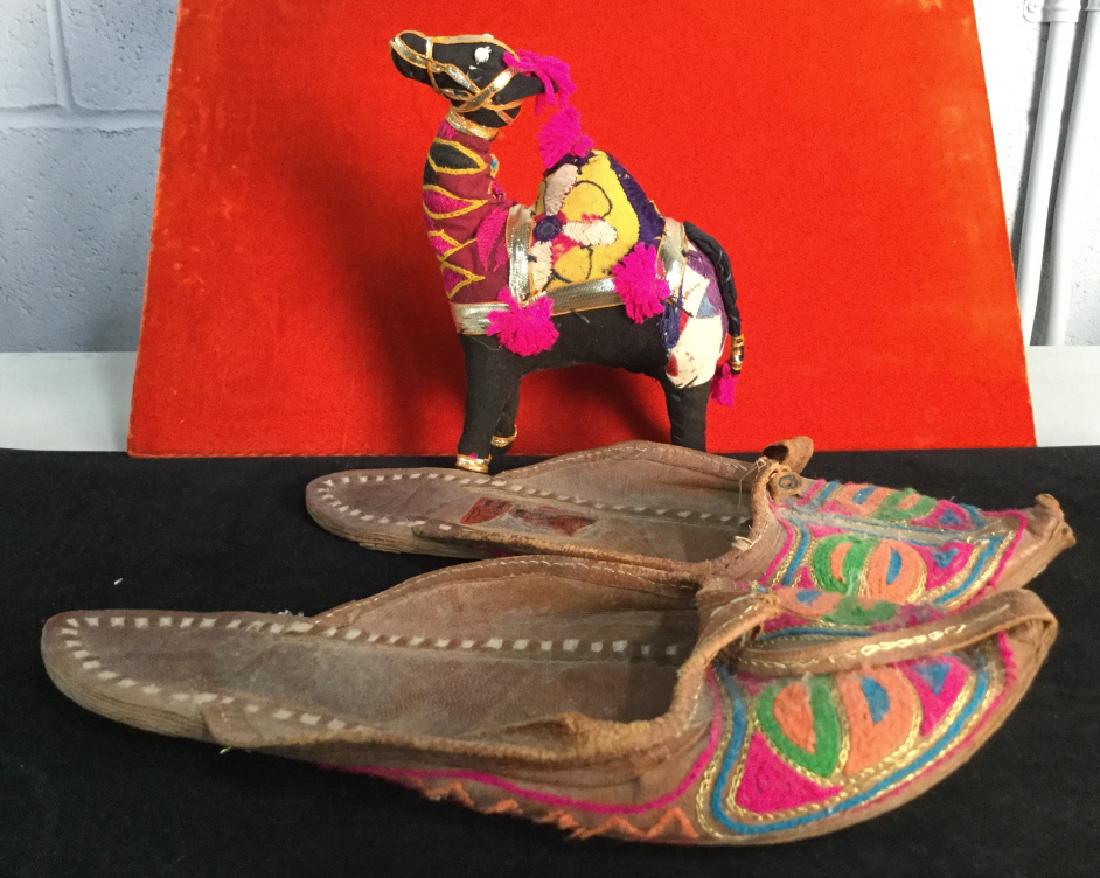 Group of Souvenir Slippers & Stuffed Toy: Group of Souvenir slippers and stuffed toy stylizedvas a camel. Both pieces are made with brightly colored fabric. Slippers are marked as genuine leather from the Kolhapuri Center in India. Slippers a