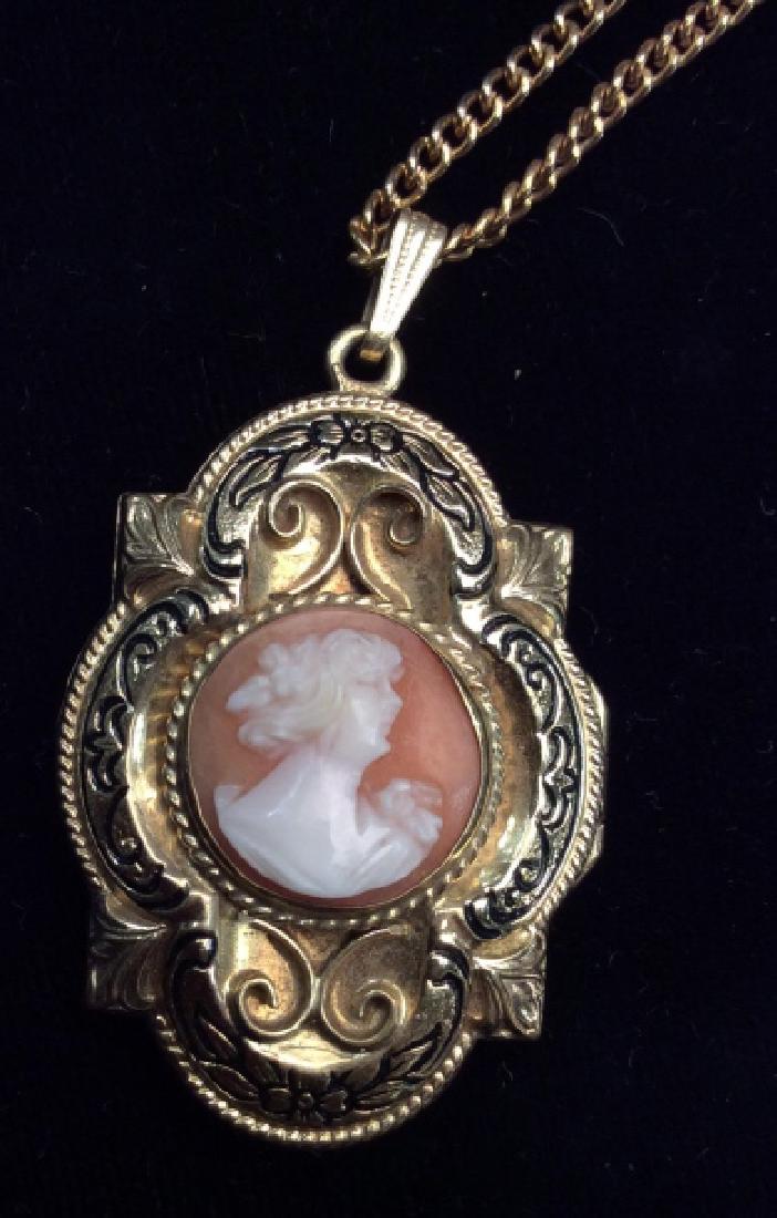 Gold Toned Metal Cameo Locket Necklace: Gold Toned Metal Locket Necklace. Gold toned metal, with etched filigree design, carved cameo portrait medallion Measures approx 14 in long, pendant measures approx 1 1/2 in by 2 in. Women’s vintage