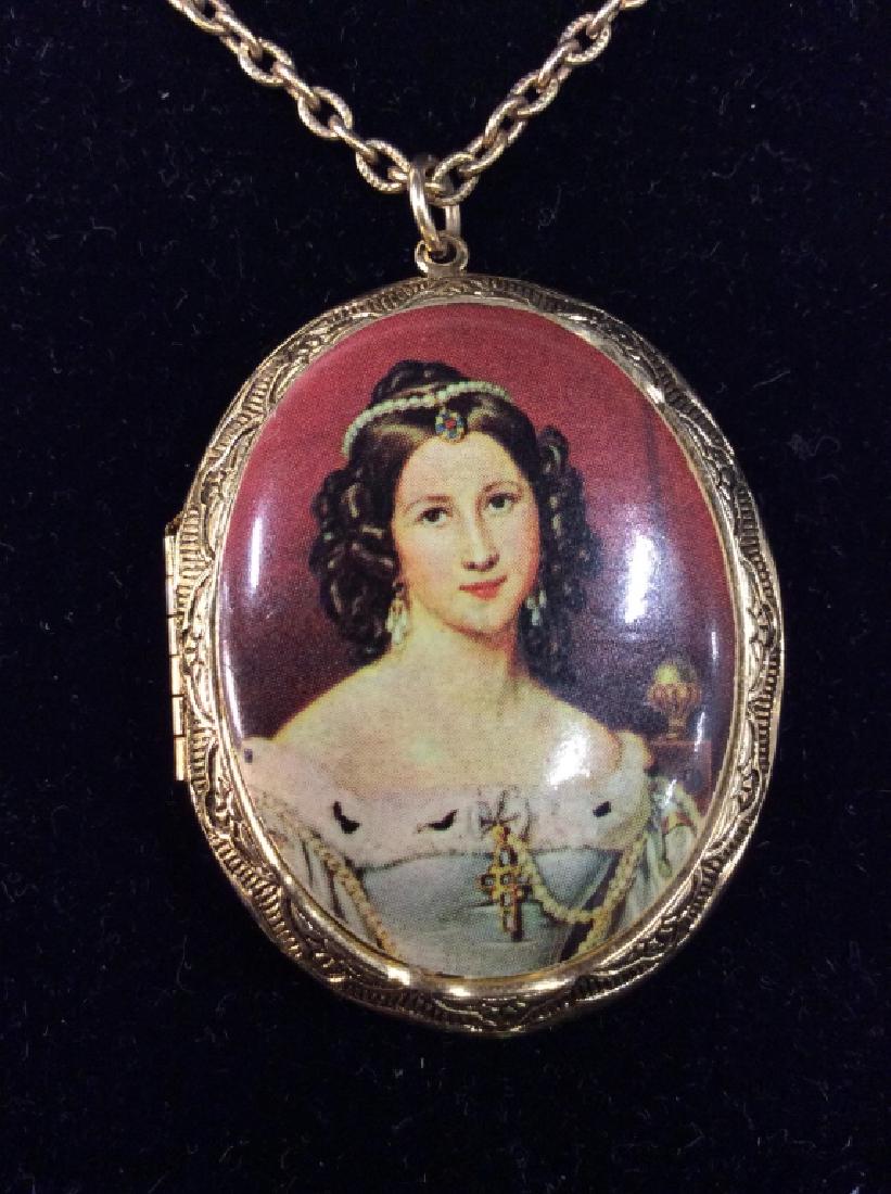Gold Toned Metal Locket Necklace: Gold Toned Metal Locket Necklace. Gold toned metal, with etched filigree design, transfer print of woman’s portrait. Measures approx 14 in long, pendant measures approx 1 1/2 in by 2 in. Women’s v