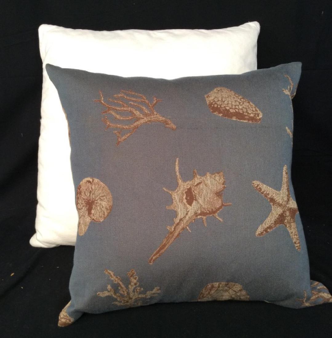 Lot 2 Decorative Throw Pillows: Lot 2 Decorative Throw Pillows. White toned fabric pillow, one blue toned fabric pillow with tan reverse side and tan and brown toned Seashell design on blue toned front. Some surface wear. Measures a