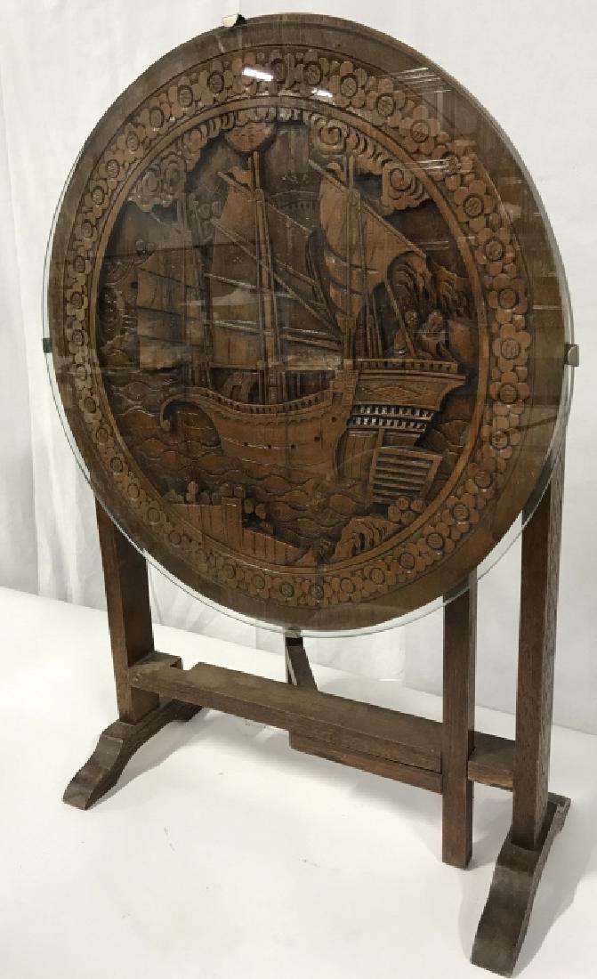 Vintage Asian Carved Mahogany Tilt-top Table: Vintage Asian Carved Mahogany Tilt-top Table, 21 in diameter of top, top has protective Glass clipped to top, table top has intricate carving of an Asian ship with figures, height 19 in, Good vintage