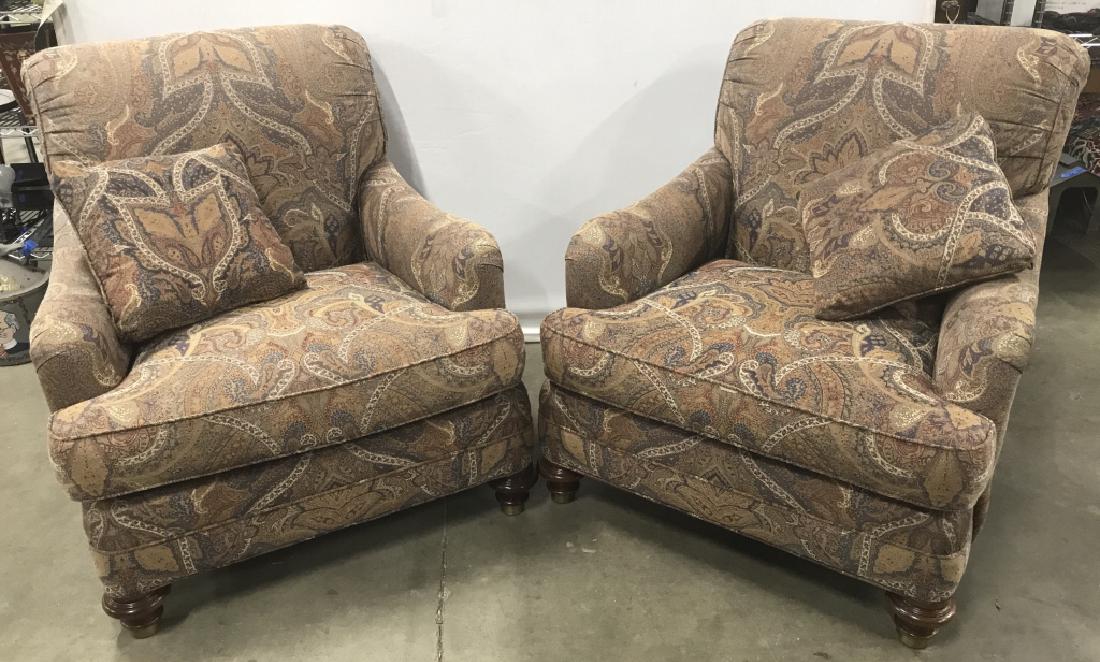 Pair Of Earth Toned Paisley Club Chairs: Pair Of Earth Toned Paisley Club Chairs with matching throw pillows and turned wooden and brass toned metal feet, measures approximately 36 inches in height x 33 inches wide x 41 inches deep, some sun