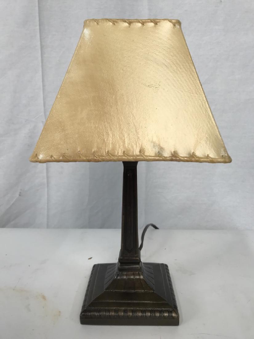 Bronze Toned Metal Lamp W Shade: Lamp is bronze toned and metal. Contains a cream toned shade that Clips,on To bulb. Measures approx 14 inche’s tall 5 inches wide without shade. Lamp, table lamp, home lighting, home accessory, offi
