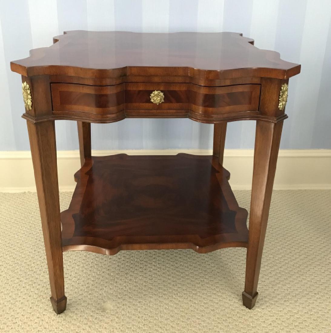MAITILAND-SMITH Marquetry Table W Ormolu: Mainland-Smith rich mahogany toned wooden table with Marquetry Design, tapered legs, Ormolu Detailing, Center Drawer, two pull out shelves with leather tops, and lower shelf. Interior of drawer has br