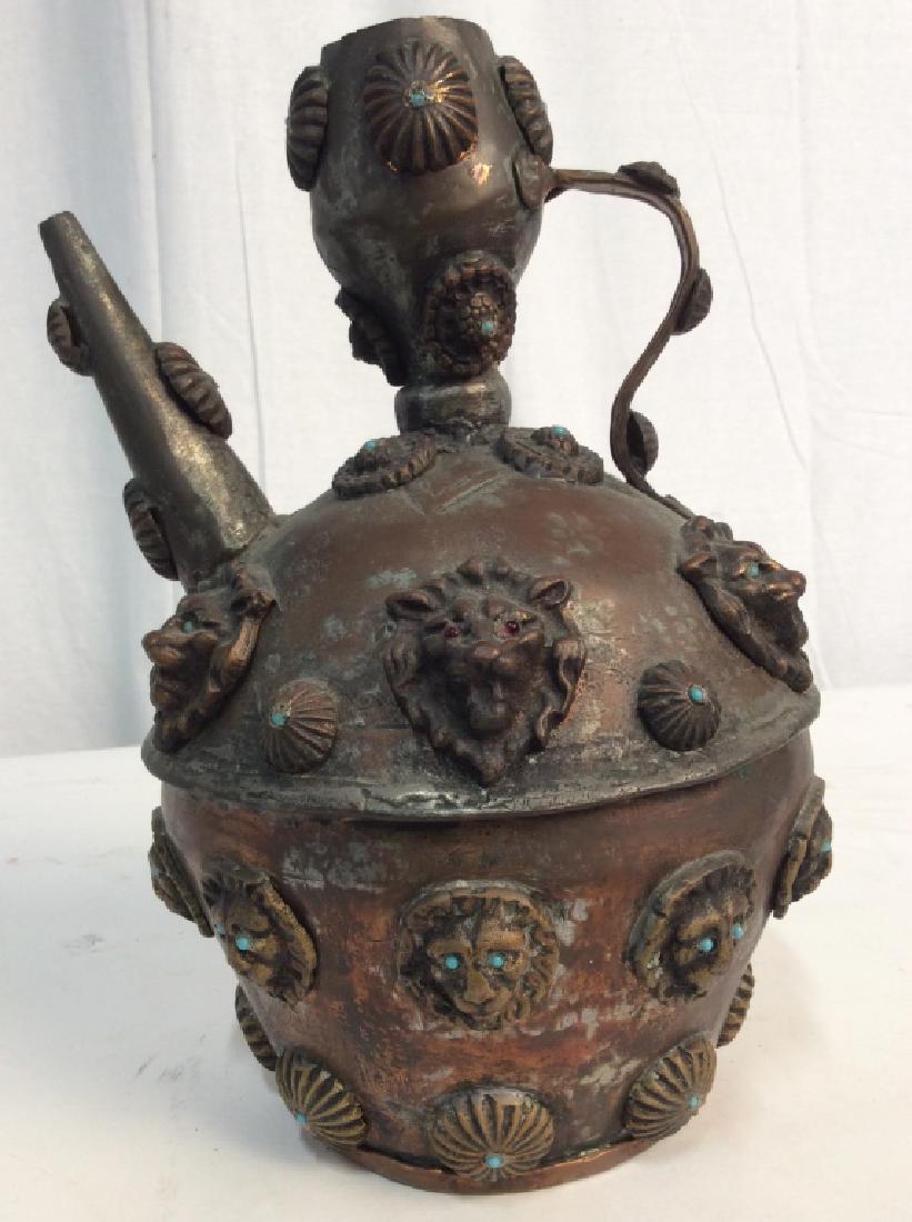 Middle Eastern Copper And Enamel Jug: Middle Eastern Copper And Enamel Jug, Decorated with lion heads and medallions with turquoise blue and garnet red enamel eyes and dots, open top with handles and spout, possibly copper, some dents, 12