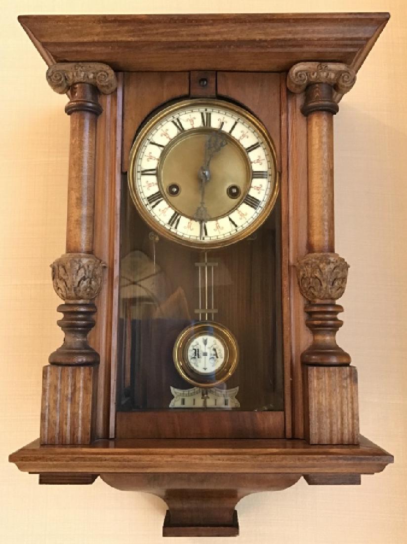 Antique Wooden Cased Wall Clock: Antique Wooden Cased Wall Clock, 20 in x 9in x 6 in, clock face sits in brass bevel, Enameled Roman Numerals, Pendellum has R A with arrow painted down, includes key which reads Waterbury clock compan