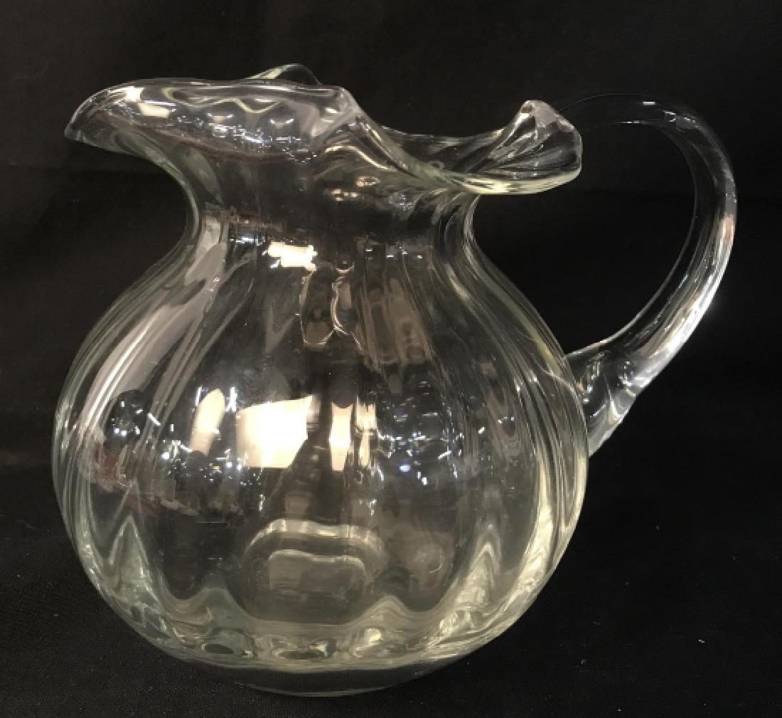 Glass Pitcher W Wave Rim Opening: Glass pitcher with wave rim opening. Approx 6 inches in height by 7 inches in width from spout to handle by 5 inches in diameter. Serveware / dishware / glassware / tabletop accessory. Property of a G