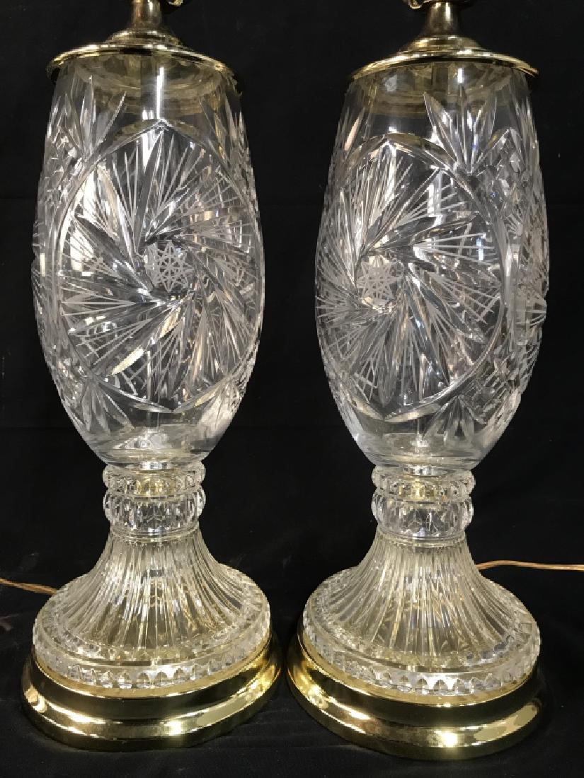 Pair of Pinwheel and Hobstar Cut Glass Table Lamps: Pair of Cut glass table lamps with pinwheel and hobstar patterns in glass. Metal Base and harp are yellow brass in tone. Measures approx 29.5 inches in height by 7 inches in diameter at base. Lamps ha