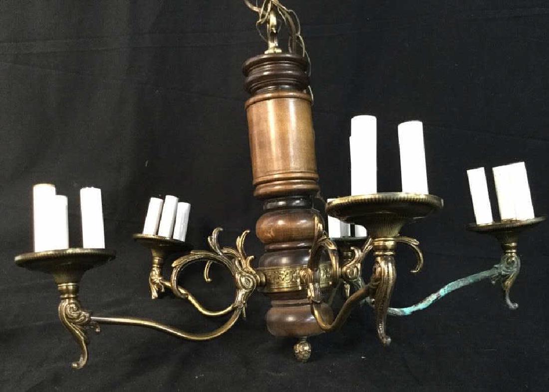 Wooden Chandelier W Bronze Arms and Detailing: Carved cylindrical Wooden Chandelier with 5 Bronze Arms. Each arm holds 3 electrified candle lightbulbs. Decorative Bronze banding around wood. Moderate discoloration / verdigris on two arms, will nee