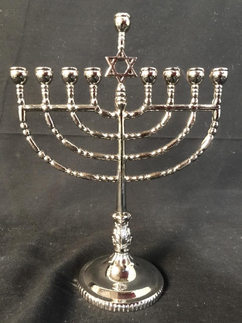 Silver Toned Judaica Menorah: Menorah is silver toned. Piece has Star of David in center. Judaica Menorah, Judaica, Hebraica. Measures approx 8.5 inches tall 6.5 inches long. 6.