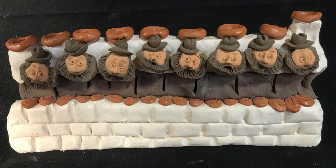 Signed Clay Ceramic Rabbi Menorah: Signed, Handmade clay ceramic rabbi Menorah. Signature on the side reads ‘ DF, Denis.’ Some cracks visible along the reverse side. Piece has been repaired, and is fragile. Measures approx 4.5 inch