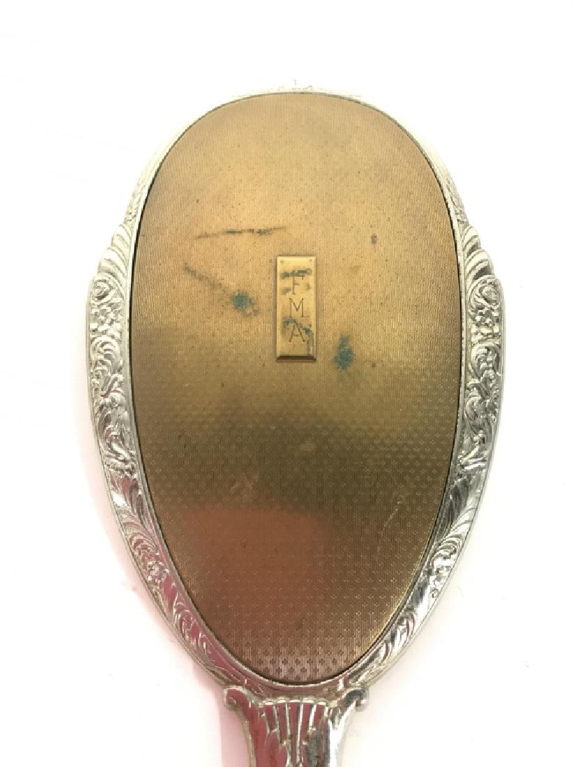Silver Plated Hand Held Vanity Mirror C 1920’s: Piece appears to be silver plated. Backside appears to possibly be brass. Reads FMA on backside. Measures approx 13 inches long 4.5 inches wide. Vanity accessory, mirror, handheld mirror 6.