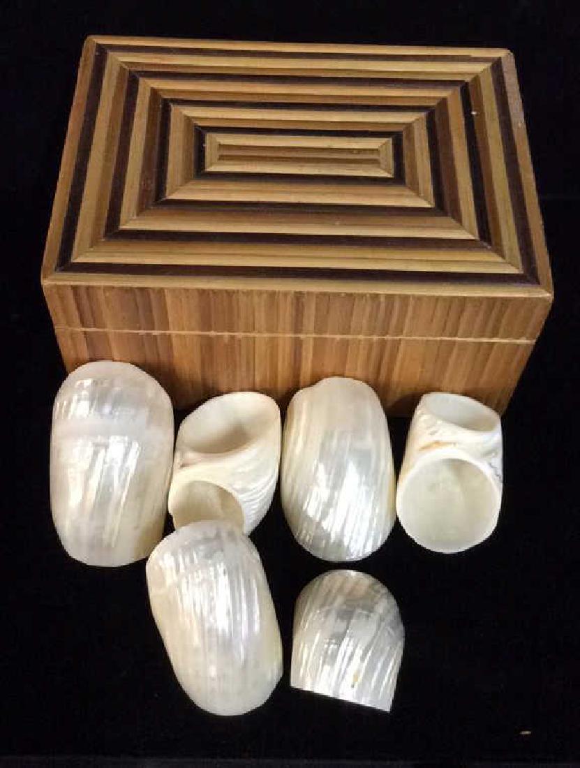 Set 13 Sea Shell Napkin Rings W Box: Set 13 Sea Shell Napkin Rings W Bo. White toned iridescent/pearlescent Seashell Napkin Holders, comes with keepsake box wi5 red toned fabric interior and wooden exterior with geometric design. Some m8