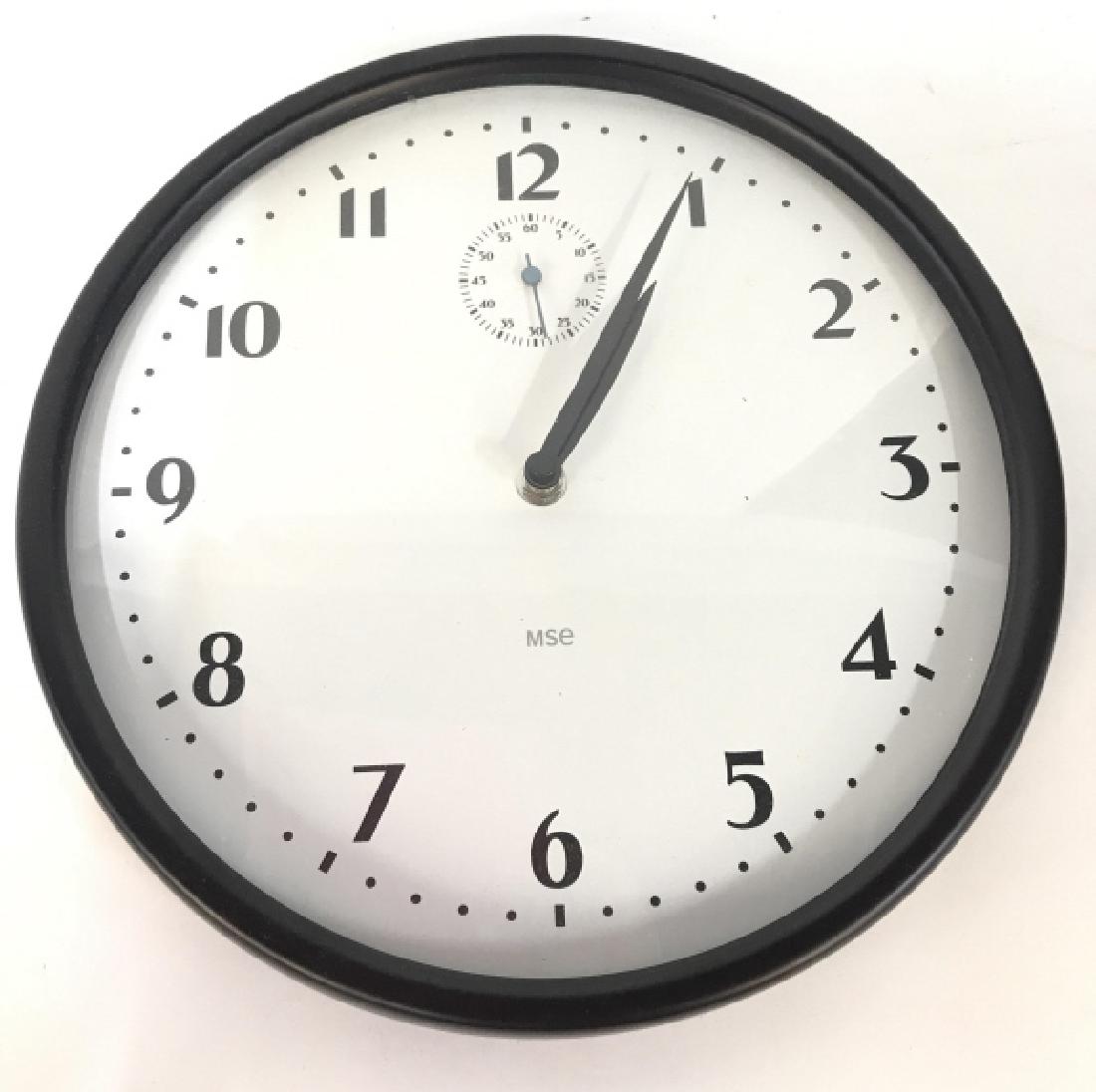 MSE Wall Clock: Clockface reads MSE. Clock frame is black toned clock face is white toned with black toned digits. Home accessory, office accessory wall clock Measures approx 11 inches diameter. 6.