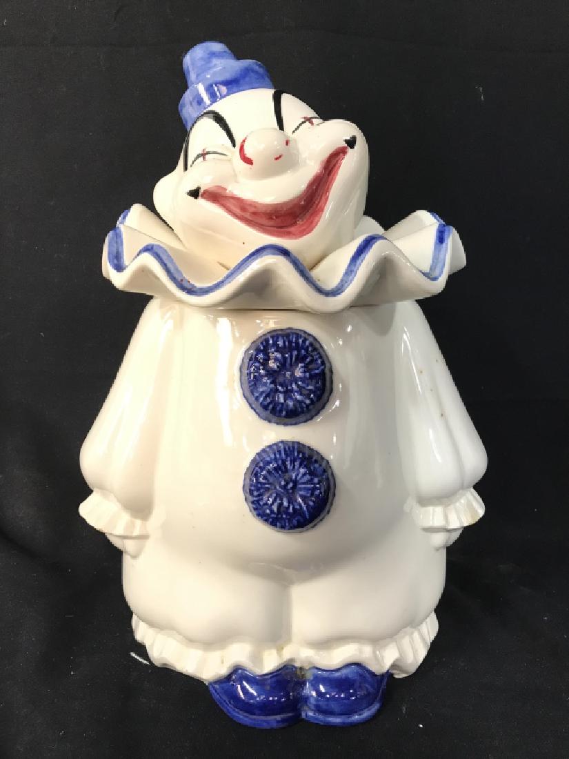 Porcelain Clown Cookie Jar: Piece is porcelain. Piece is shaped and painted to resemble a clown. Possibly hand painted. Head portion of jar is lid. Measures approx 13 inches tall 8.5 inches wide 7 inches deep. Has illegible mark