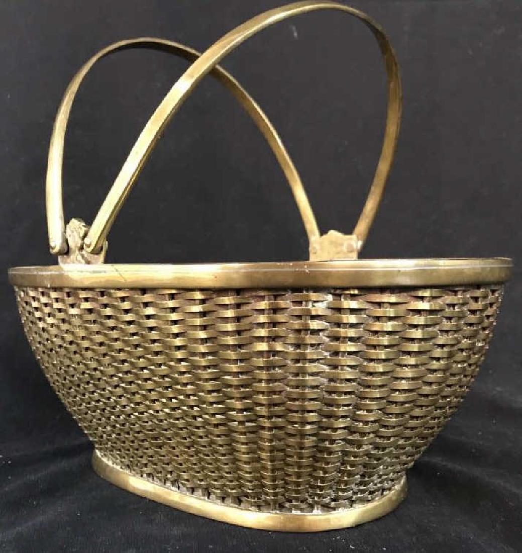 Gold Toned Brass Basket: Piece is gold toned and brass. Contains woven detail. Handles are movable. Measures approx 12 inches long 8 inches deep 9 inches tall. tableware, tabletop accessory, decor piece, decorative accessory.