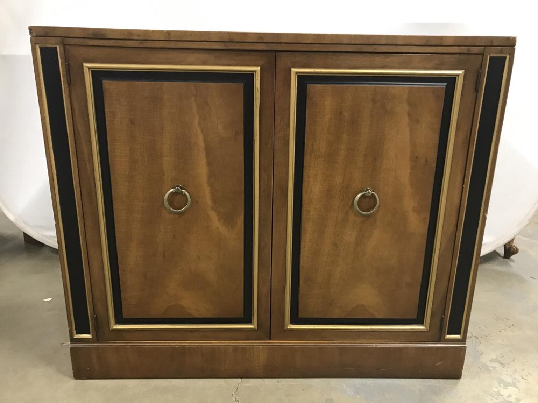 HERITAGE Brand Wooden Cabinet Credenza: HERITAGE brand wooden Credenza. Two cabinet doors open to reveal shelf interior with two drawers. Exterior front facing surface has black and gold tone details. Credenza measures approx 38 inches in w