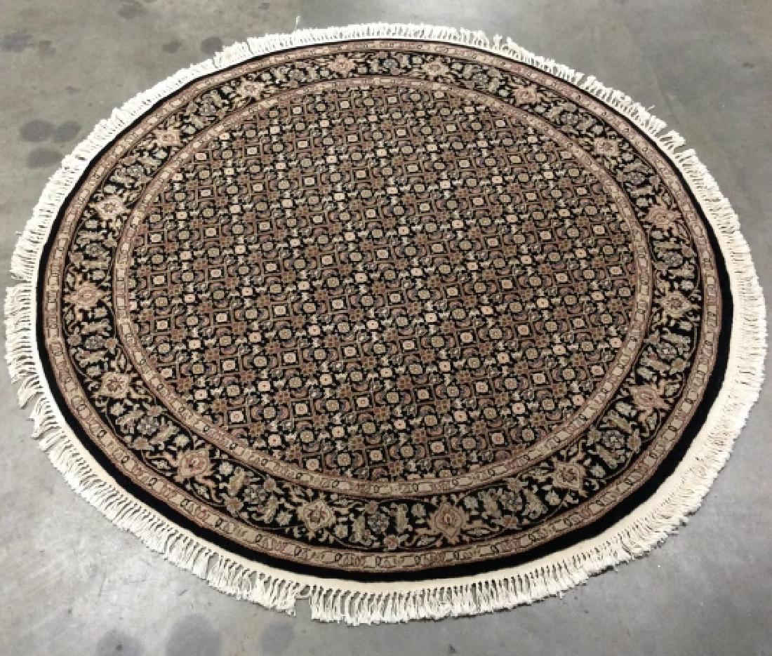 Handmade Fringed Circular Wool Rug: Rug is handmade and wool. Rug has fringes. Rug is black toned with geometric, floral, leaf & vine detail with tones of beige, olive, tan, black, cream & slate blue. carpet, area rug, home decoration, 