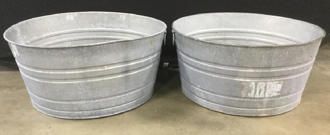 Pair Metal Silver Toned Handled Vats: Lot includes 2 silver toned vats with handles. Appear to be vintage. Up-cycled ice bucket, planter, garden accessory tub. Pieces measure approximately 25 inches wide 12 inches tall. Contains some evid
