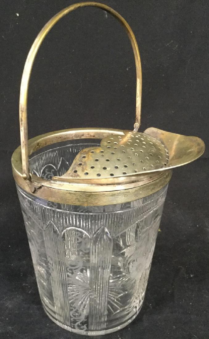 Cut Crystal Ice Bucket W Filter: Ice bucket appears to be cut crystal. Has silver toned rim with handle and filter. Measures approx 12 inches tall 7 inches wide. Contains frosted floral & vine detail. Bar Ware, tableware, crystal tab