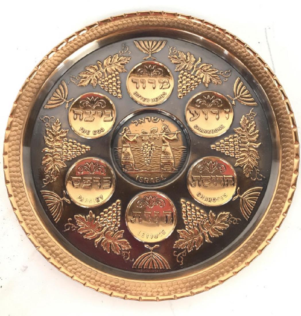 Copper Toned Metal Judaica Seder Plate: Seder plate is metal and copper toned. Piece has hanging loop on backside. Contains Hebrew characters. Judaica, Hebraica, Seder Plate, ceremonial tableware. Measures approx 9.5 inches diameter. 6.