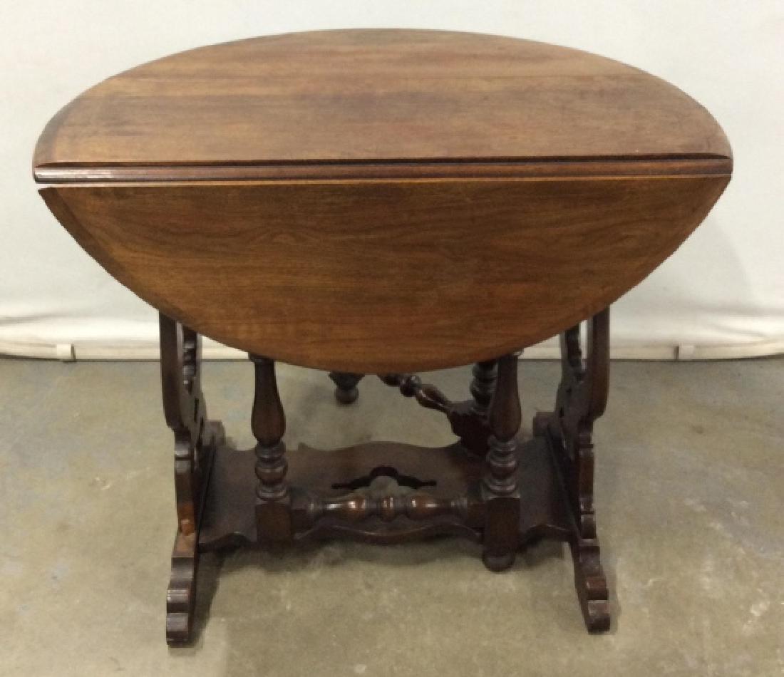 Vintage Drop Leaf Circular Table W Carved Base: Vintage Wooden Drop Leaf Circular Table W Carved And turned base, measures approximately 30 inches in diameter x 24.5 inches tall, some surface scratches and nicks to wood. Vintage Side Table, Dark To