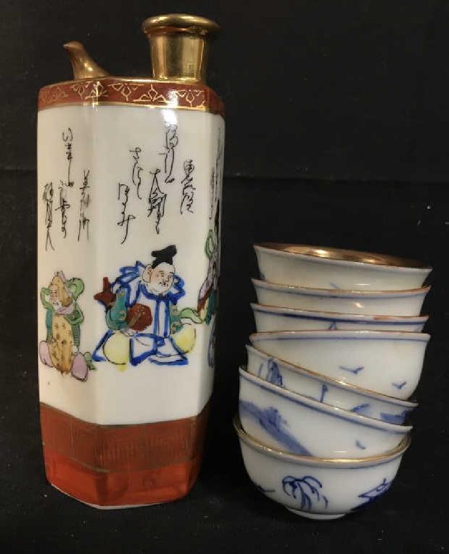 Signed Asian Porcelain Sake Whistling Flask W Cups: Signed Asian porcelain sake porcelain set, including flask / carafe / pitcher and 7 cups. sake pitcher features a bird on top that whistles as steam rises. Set features hand painted figures along with