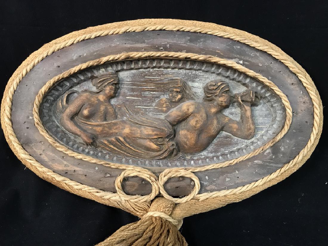 Carved Wood Art Wall Hanging, 3 Figures In Flight: Carved Wood Art Wall hanging, with exaggerated natural fiber tassels. Motif in Carved wood depicts three figures in flight, one with a trumpet. Oval wood carving measures approx 13.5 inches in height 