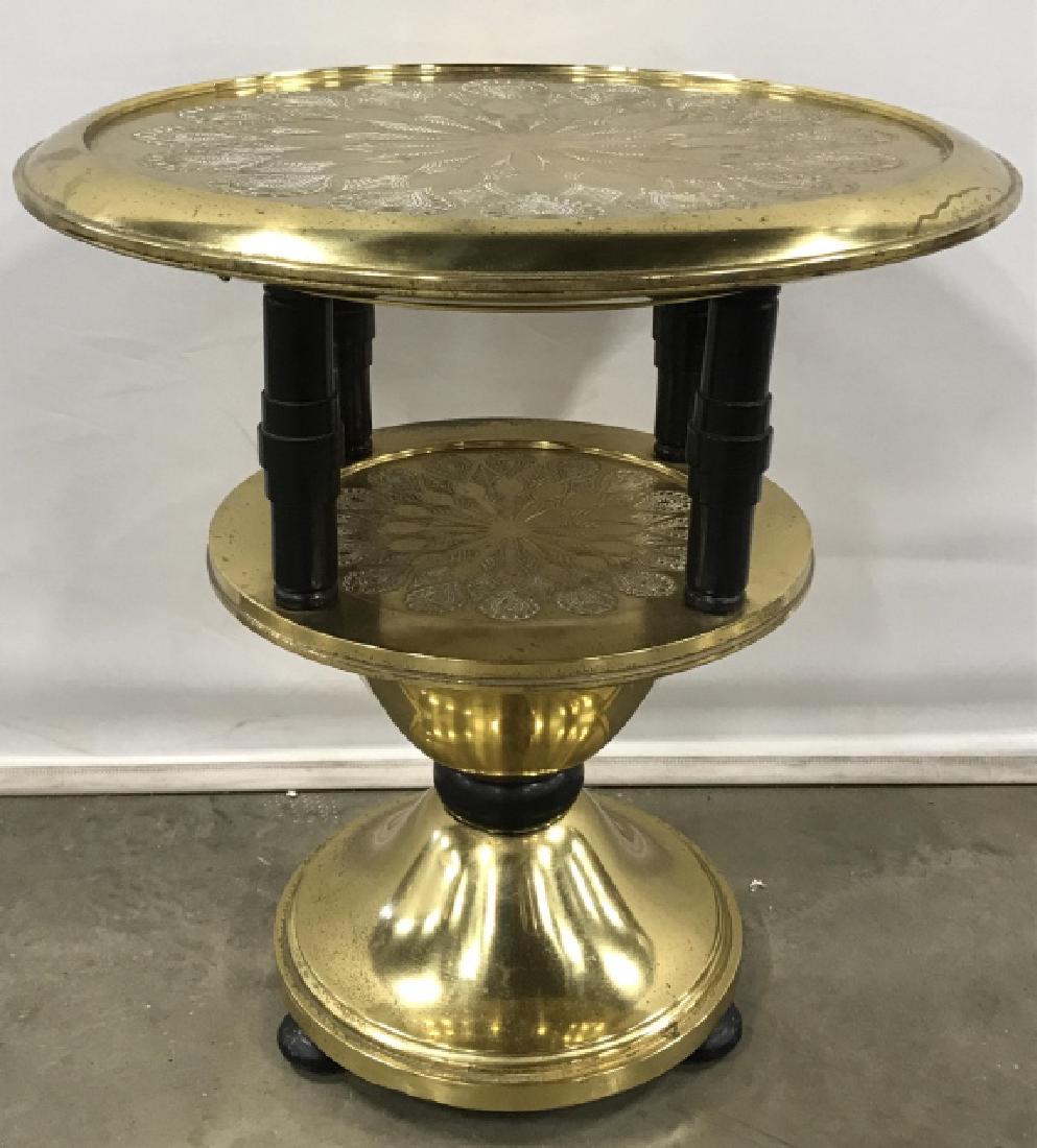 Vintage Black & Gold Toned Brass Table: Table has Round shape. Piece is gold and black toned. Tabletop and middle platform have geometric pattern detail. Has 3 black toned bun feet. Measures approx 26 inches tall 24 inches wide. Side Table,