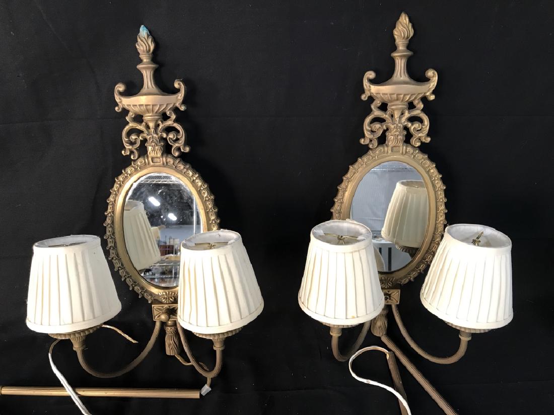 Pair Wall Sconces With Electrified Candelabras: Pair of Scroll and Leaf designed brass toned Metal Wall Sconces With Mirror backs, electrified candelabras, And cream toned lined shades. Measures approx 20.5 inches tall x 12 inches wide. Switch miss