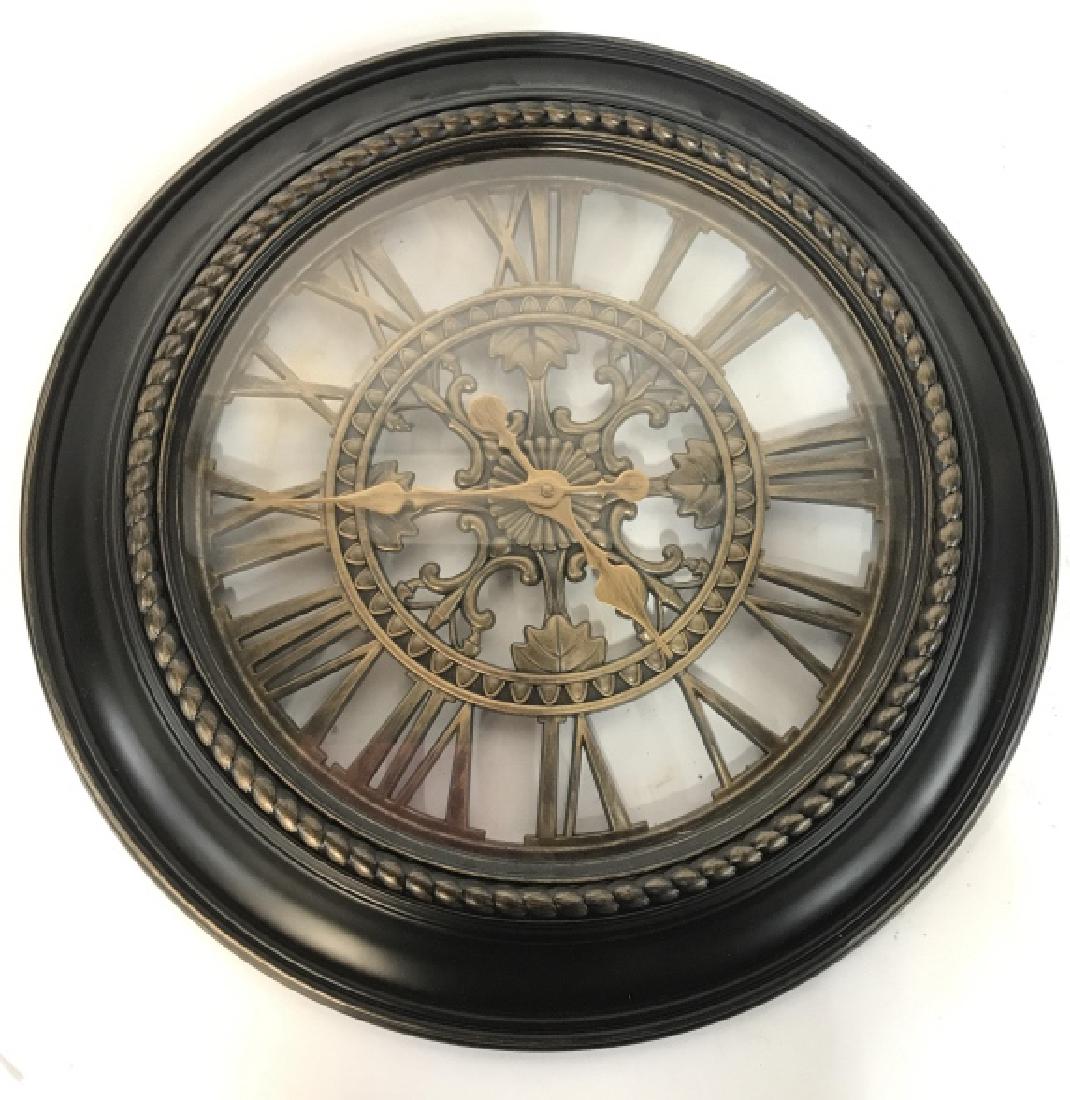 Black & Gold Toned Wall Clock: Wall clock is black and gold toned. Contains gold toned ornate and Roman numeral detail. Frame of clock is black toned. Measures approx 23 inches diameter. Home accent, wall clock, wall hanging, home