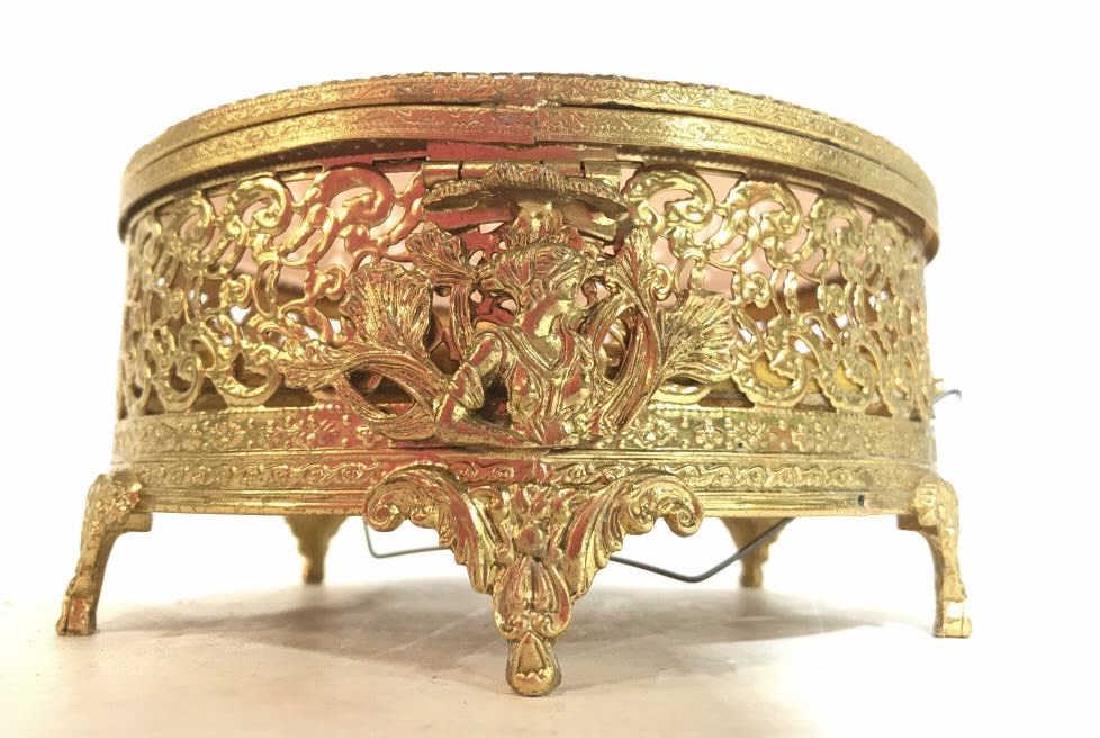 Gold Toned Circular Ornately Detailed Jewelry Box: Piece is gold toned and ornately detailed. Contains lid. Piece is also footed. Measures approx 6.5 inches wide 3.5 inches tall. Contains pieced detail. Sugar casket, keepsake jewelry box, vanity acces