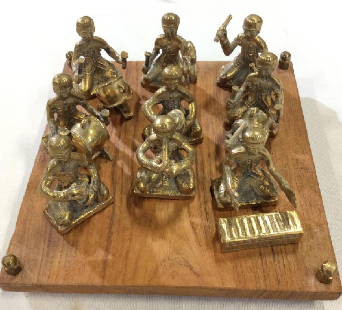 14 pc set Cast Metal Character Band: 14 pieces including 9 musicians, 4 instruments, and wooden base with metal feet, gilt metal, possibly bronze. Base measures app in square, figures measures approx 3 in tall. Asian arts and crafts, dec