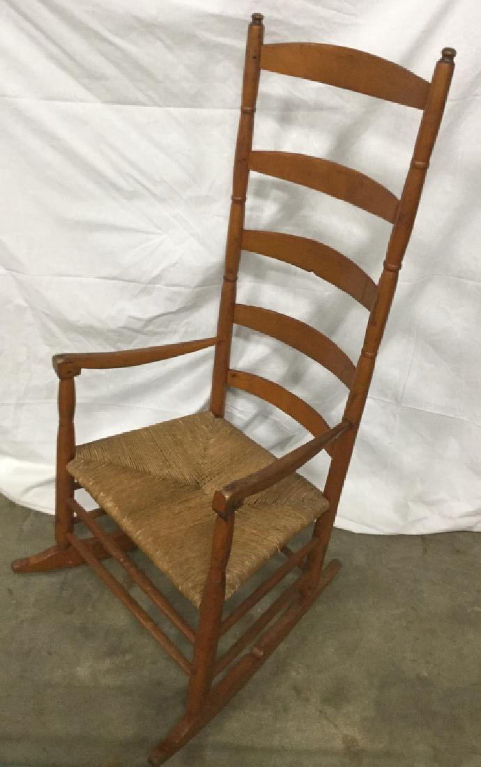 Vintage Ladder Back Rocking Chair W Rush Seat: Wooden rocking chair has some fading of color/surface wear of wood. Some minor cracks in wood. Measures approx 48.2 inches in height by 22 inches in width by 16 inches in depth. Vintage wooden rocking