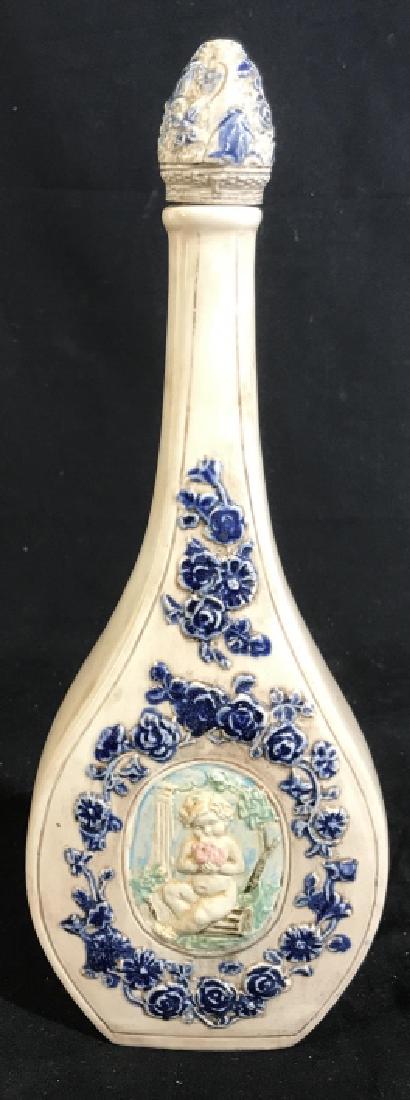 Old English Porcelain Bottle w Cherub Relief: Center medallion has cherub, putti child seated in swing in garden setting, floral relief adorns porcelain bottle measures ht 14 inches has stopper, bottle, decanter, vessel, tableware