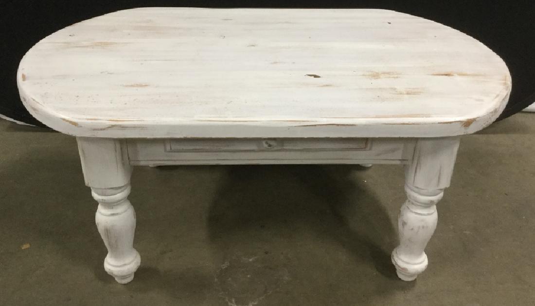 Wood Stadium Oval Coffee Table W Drawer: Coffee table is distressed white in tone. Measures approx 18.5 inches in height by 43 inches in width by 27 inches in depth. Some minor surface wear of wood, possibly stylistic. Coffee table, interior