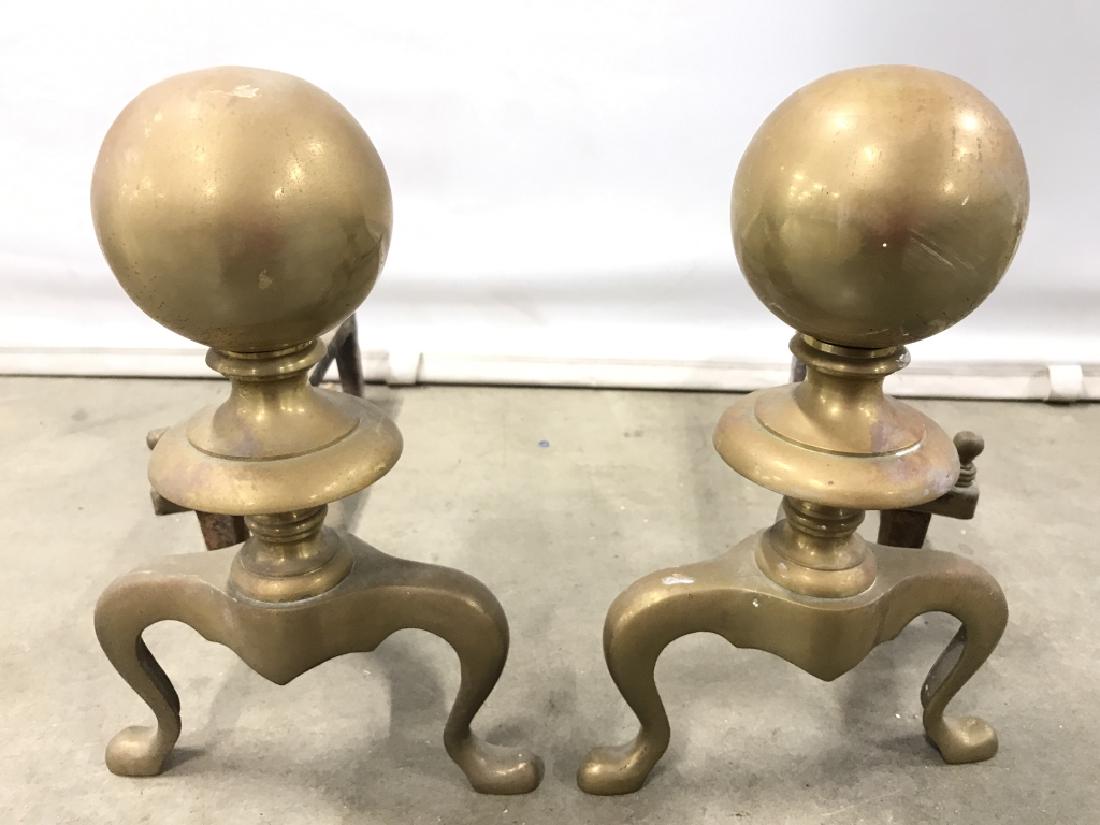 Pair Brass & Wrought Iron Andirons Tops of Andirons are: Tops of Andirons are gold toned and have spherical shape. Each measures approx 17 inches long 12 inches tall 7 inches wide. Contains evident wear & rusting. Home accent, andirons, firplace accessories