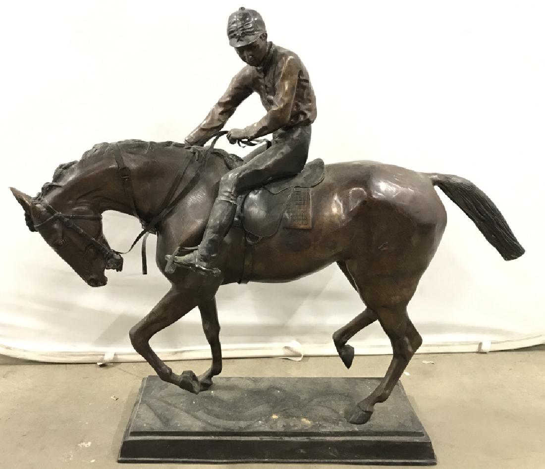 Bronze Toned Metal Jockey On Horse Statue: Piece is possibly bronze. Depicts a jockey riding a horse. Base is black toned. Jockey statue, horse statue, metal horse statue. Measures approx 41 inches long 36 inches tall 10 inches wide. animal st