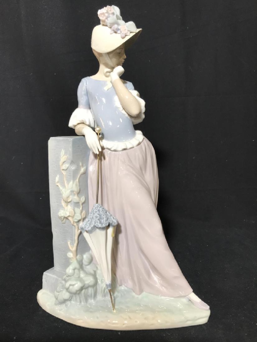 LLADRO Lady With Umbrella Figural: Underside of piece reads LLADRO HANDMADE IN SPAIN. Depicts a female figure leaning on a wall holding an umbrella. Measures approx 15 inches tall 8 inches deep 6 inches wide. Umbrella needs gluing back